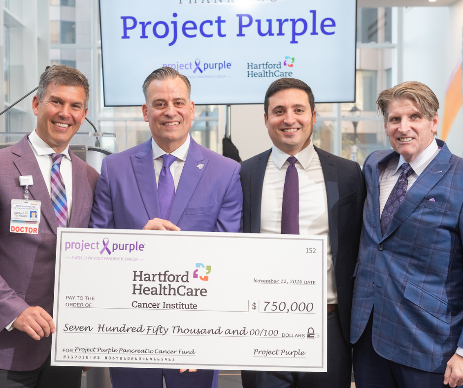 Dr. Bret Schipper, Project Purple CEO Dino Verrelli, Project Purple Board Treasurer Alex Palios, and Project Purple Board Mamber Jay Buth (who is a pancreatic cancer survivor) pose with the ceremonial check to celebrate this grant.