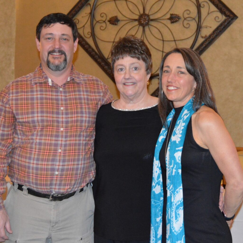 Amy Nugent standing beside Jill (her mom), and her dad.