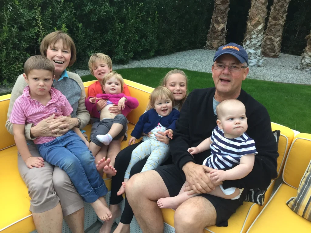 Bob Schriver seated on a patio couch with his wife and 6 of his grandchildren